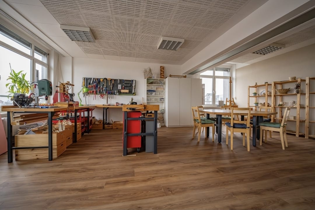 Helle Werkstatt mit Werkbänken, Werkzeugen und einem großen Arbeitstisch